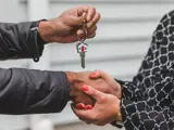 Man geeft sleutel aan vrouw.